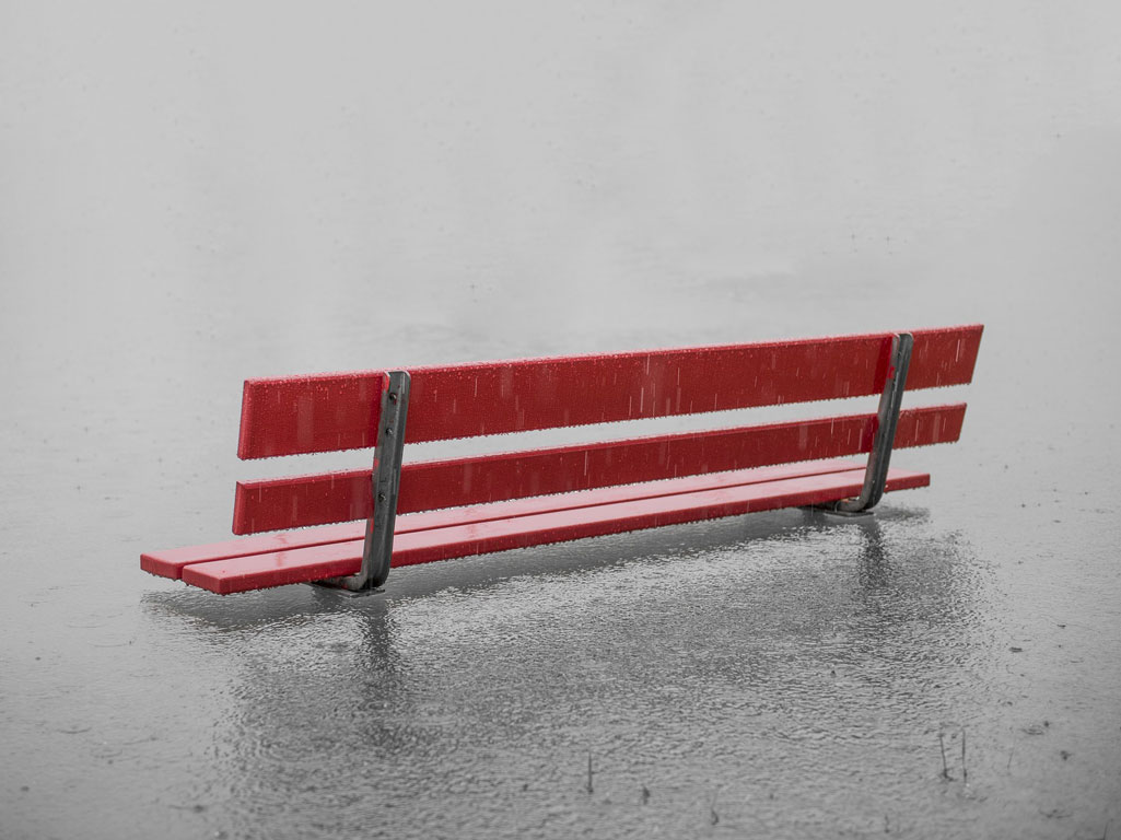 Park bench submerged in flood water and rain