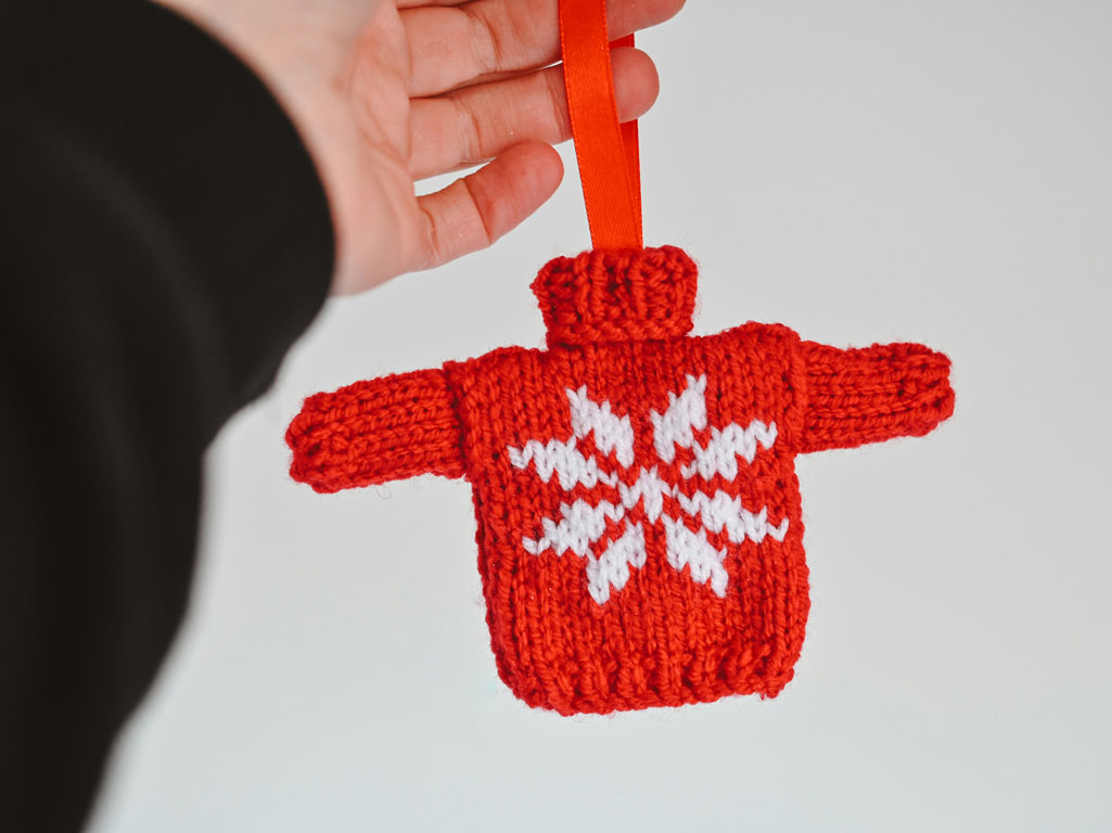 Hand holding a holiday sweater ornament